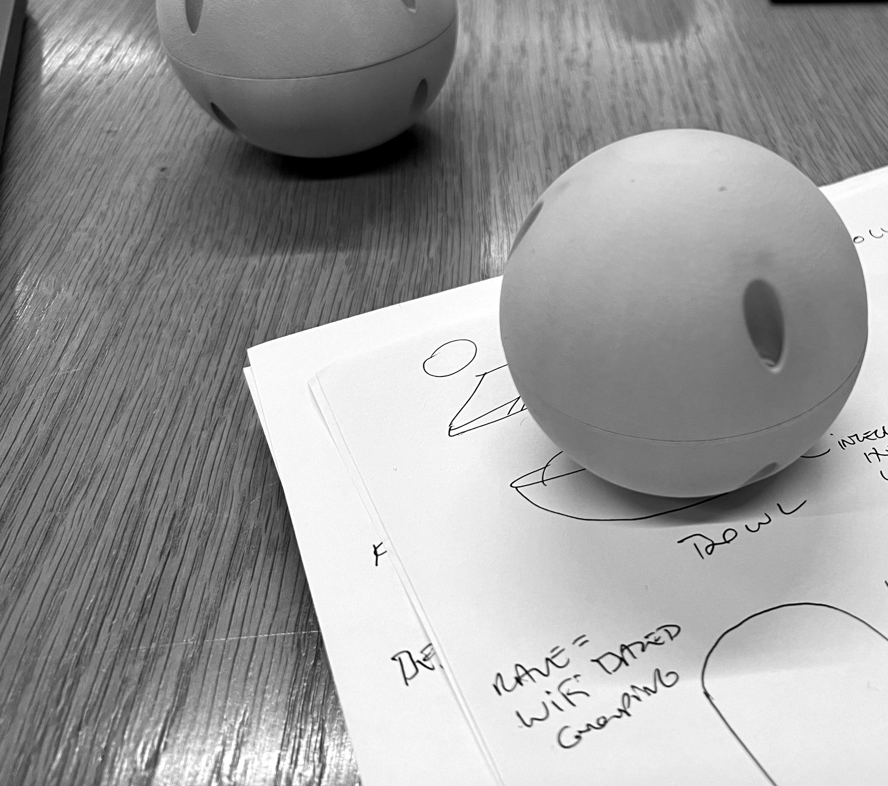 Grey foam models of a round device beside pencil sketches