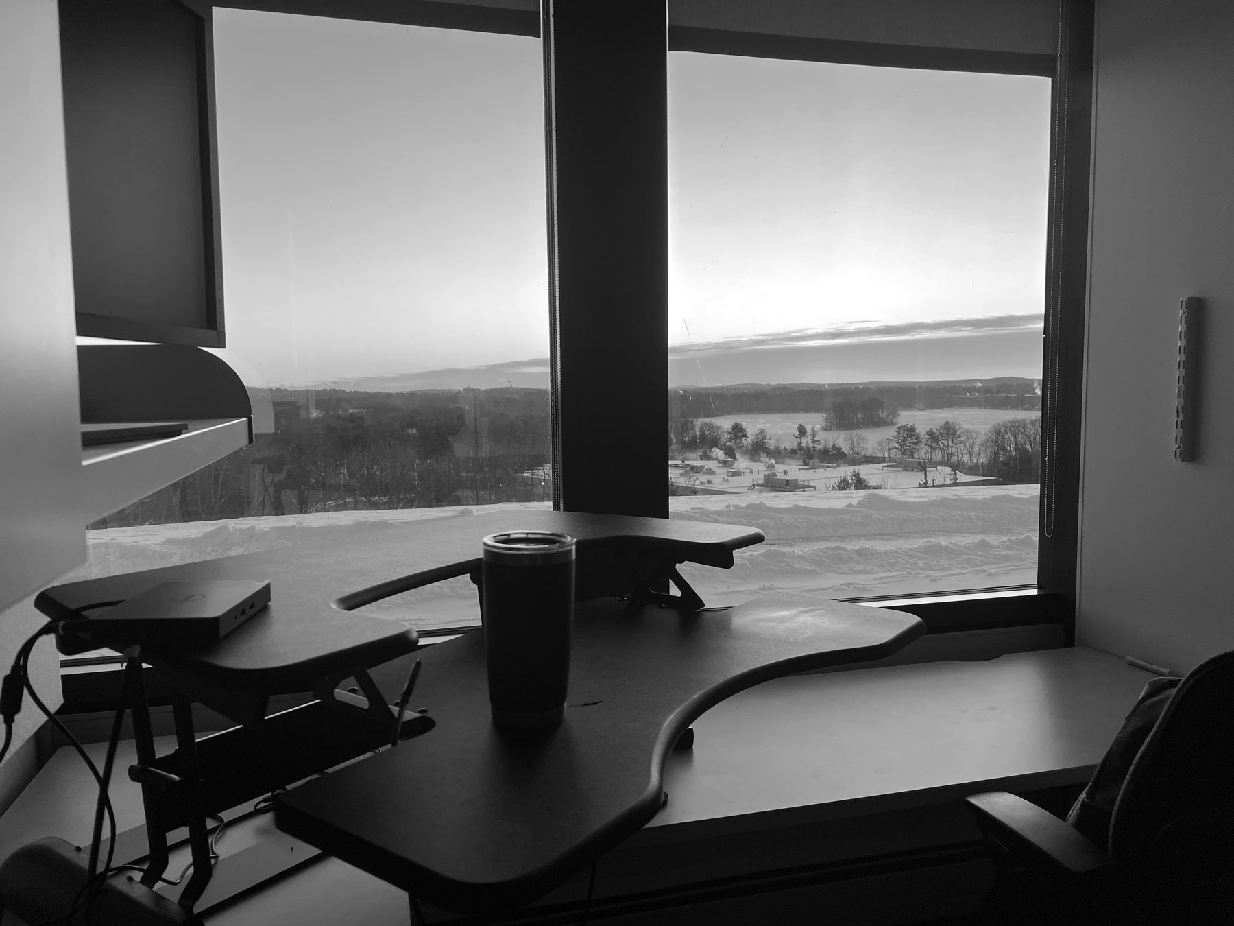 A standing desk by a window at sunrise, snow outside